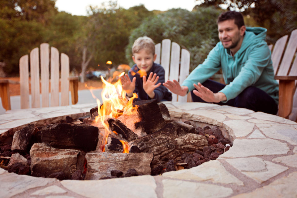 view of firepit and happy smiling family of two, father and son,.