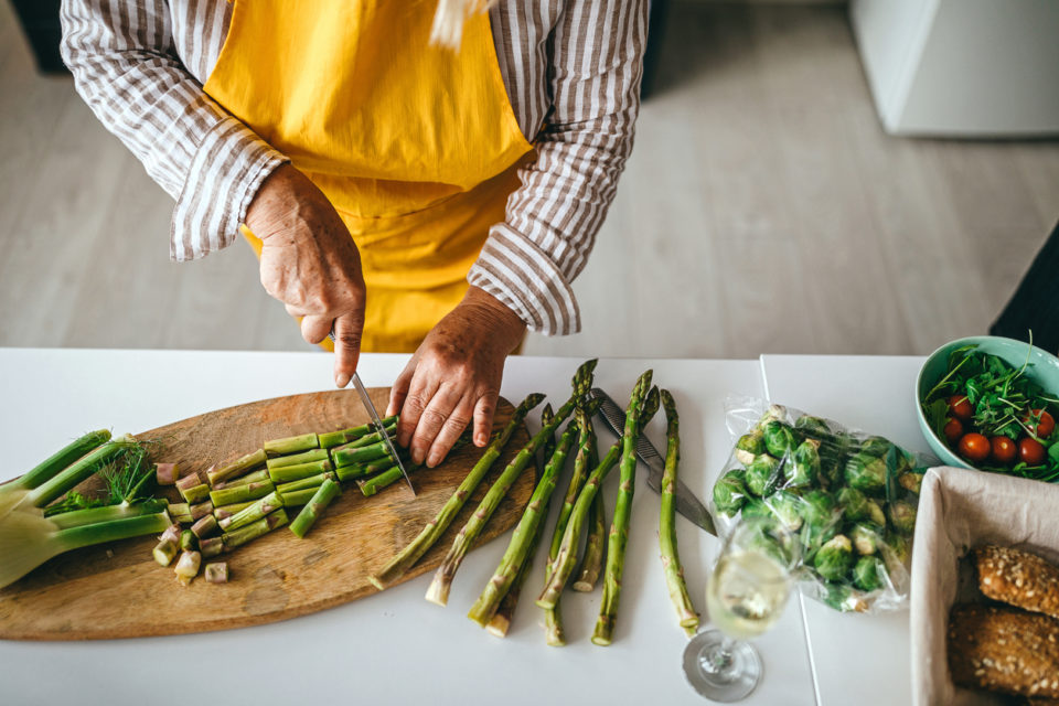 Senior woman cutting vegetable in kitchen