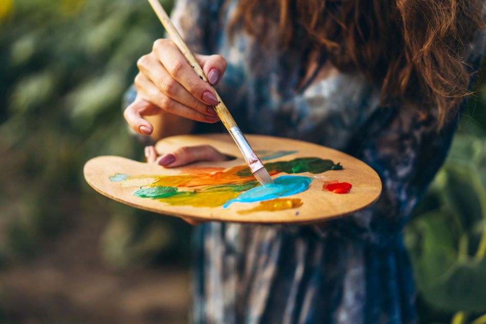 Close up hands of female artist holding brush and palette