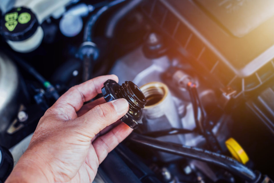 close up of man hand holding cap of brake fluid reservoir tank while checking brake fluid level in an engine