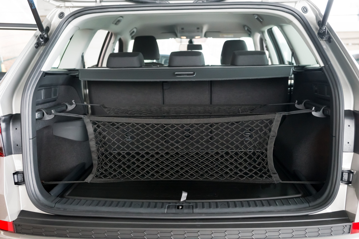 The luggage net for groceries hangs in the open trunk of the car.