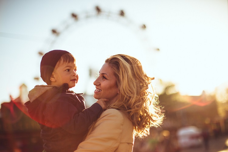 Mother and son enjoy on a sunny day in the amusement park. The Viennese Prater Wheel in the background.