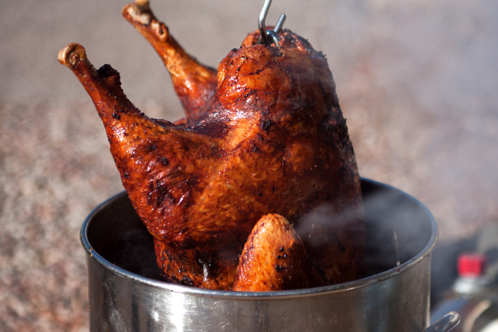 Hot fresh and delicious turkey being removed from a deep fat fryer after being cooked for a holiday celebration.