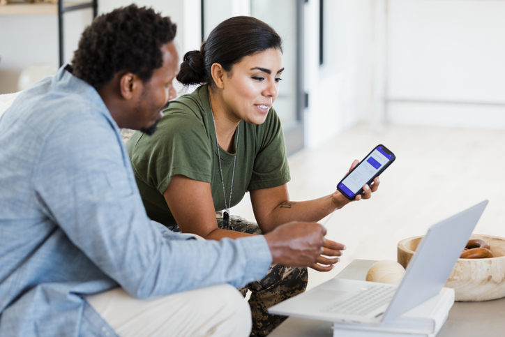 A female soldier and her husband use a banking app to check the state of their finances before the woman leaves for a military assignment.