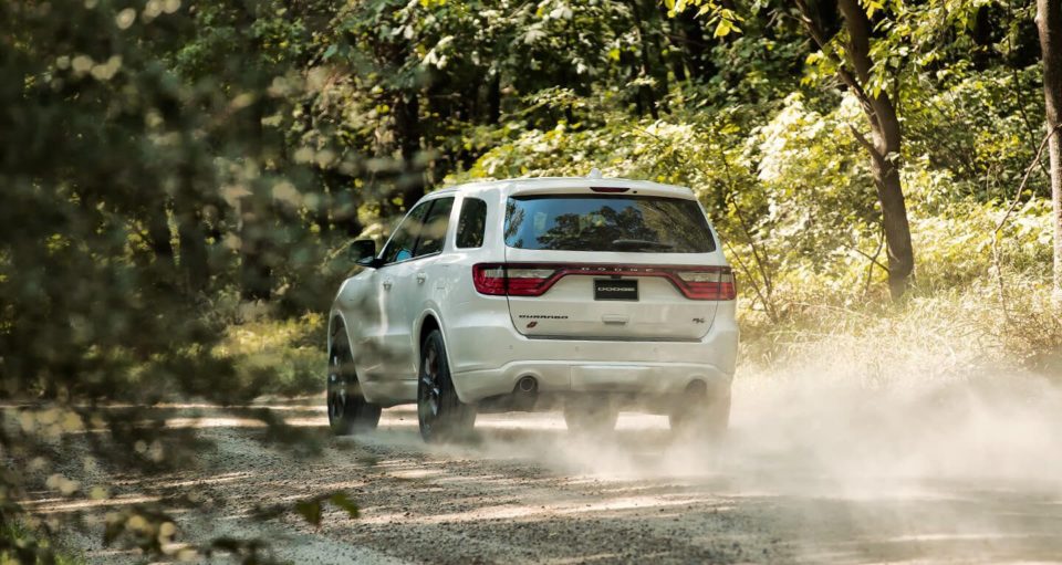 Back view of a white 2020 Dodge Durango driving on a wooded road