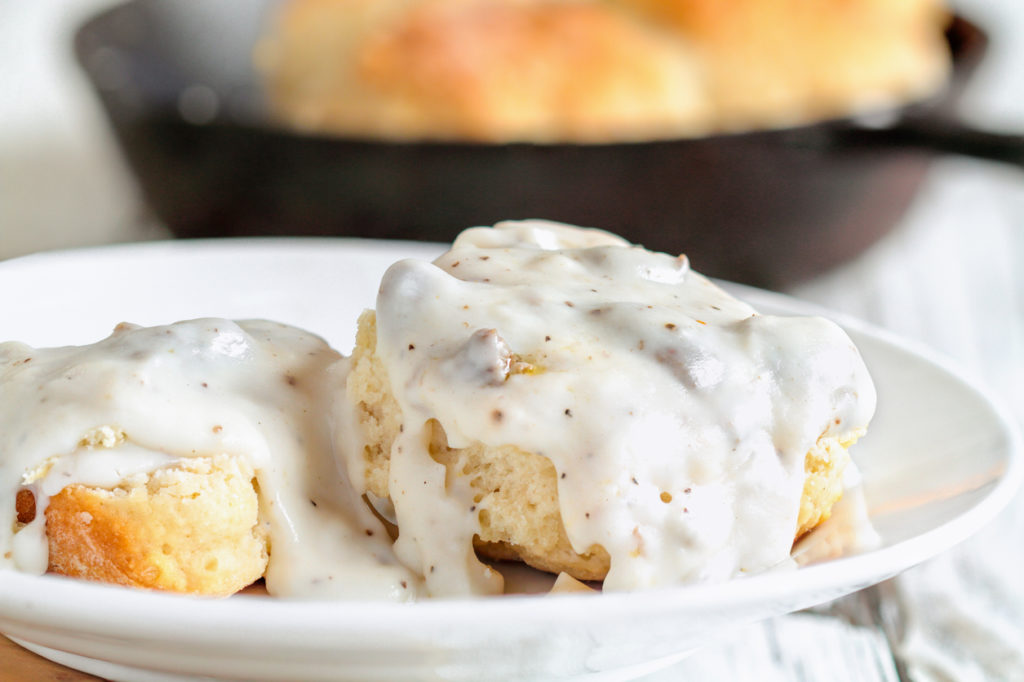 American biscuits from scratch covered with thick, white sausage gravy.