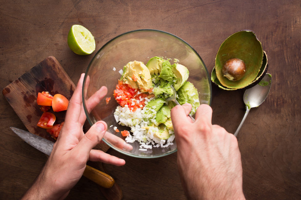Mashing vegetables to make guacamole on wooden table