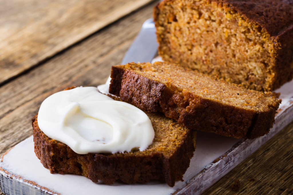 Homemade pumpkin bread with cream cheese icing sliced and ready to eat on rustic wooden table, delicious breakfast